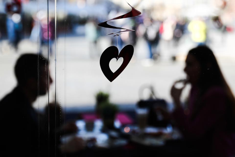 Dekorasi berbentuk hati dan pasangan duduk di meja di restoran, sehari sebelum Hari Valentine, di Krakow, Polandia pada 13 Februari 2022 (Foto oleh Jacob Borzeki/Noor Foto via Getty Images)