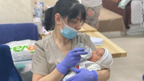 Seorang pengasuh di klinik surrogacy memberi makan bayi yang baru lahir menunggu untuk dijemput oleh orang tua baru mereka.