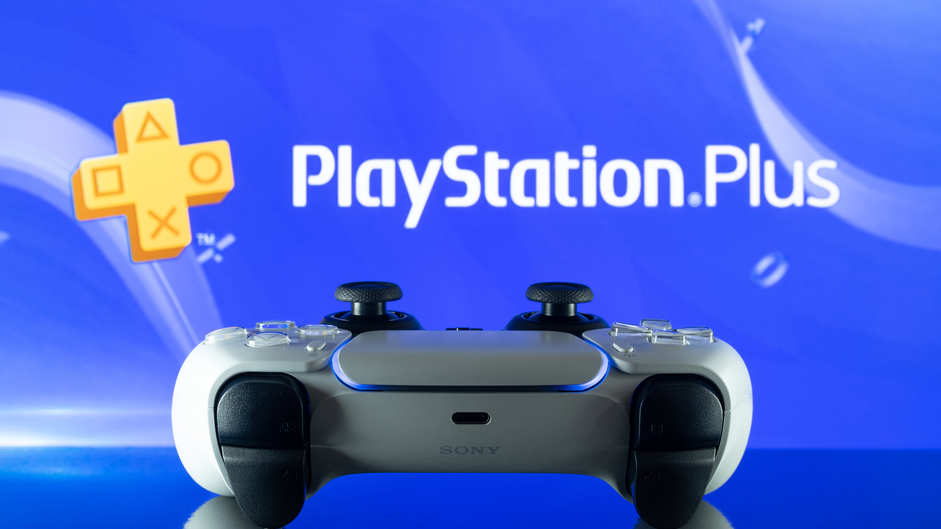 Kontroler DualSense PS5 di depan logo PlayStation Plus