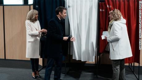 Presiden Prancis Emmanuel Macron (tengah), di samping istrinya Brigitte Macron (kiri), berbicara dengan seorang warga sebelum memberikan suara pada putaran pertama pemilihan presiden pada hari Minggu.