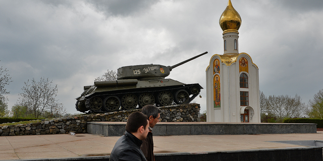 Orang-orang melewati tank era Soviet, yang sekarang menjadi monumen untuk merayakan kemenangan Tentara Merah atas Jerman yang fasis, di Tiraspol, kota utama wilayah Trans-Dniester yang memisahkan diri di Moldova, pada April 2014.
