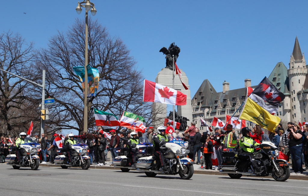 Polisi dengan sepeda motor melewati demonstrasi, bagian dari seruan demonstrasi ala konvoi "guntur bergulir" Di Ottawa, Ontario, pada Sabtu, 30 April 2022.