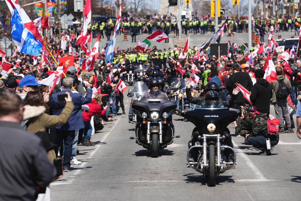 Para pengunjuk rasa bersorak saat pengendara sepeda motor melewati demonstrasi, bagian dari seruan demonstrasi gaya karavan "guntur bergulir"di Ottawa, Sabtu 30 April 2022