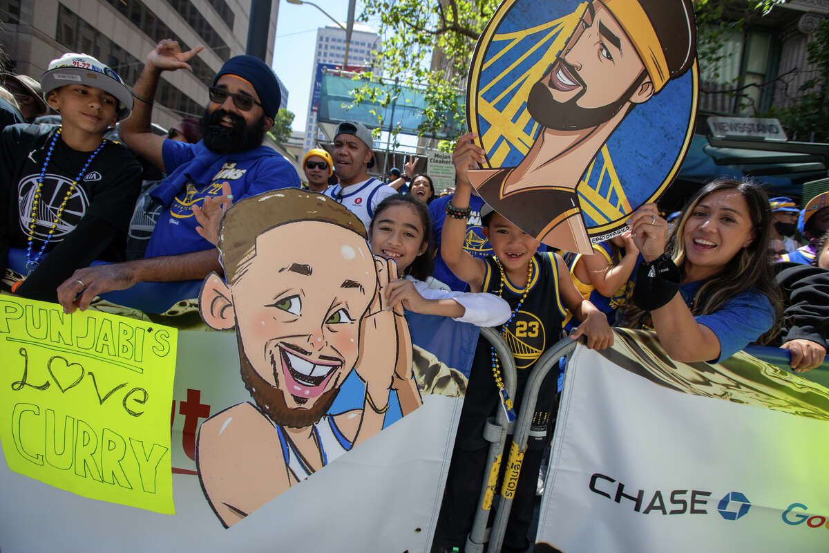 Penggemar Warriors memegang spanduk selama Parade Kejuaraan Golden State Warriors di Market Street di San Francisco, California pada 20 Juni 2022.