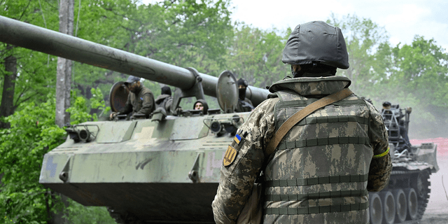Seorang tentara Ukraina melihat howitzer self-propelled di jalan di wilayah Kharkiv pada 17 Mei.