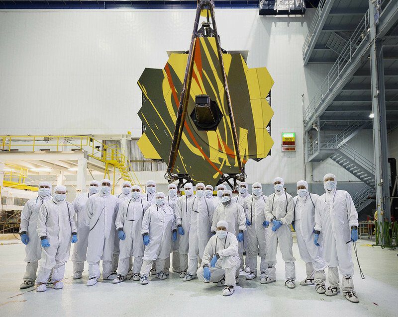 Para ilmuwan berdiri di depan Teleskop Luar Angkasa James Webb