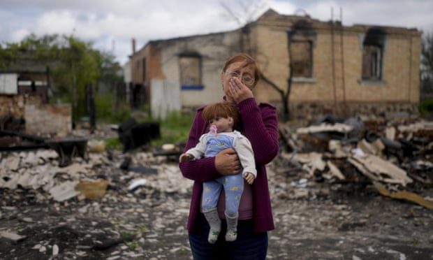 Nella Zelenska memegang boneka milik cucunya di depan rumahnya yang hancur di Potashnya, di luar Kyiv, Ukraina, pada bulan Mei.