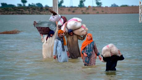Sebuah keluarga pengungsi mengarungi daerah banjir di Jafarabad, sebuah distrik di provinsi Balochistan barat daya Pakistan, pada 24 Agustus.