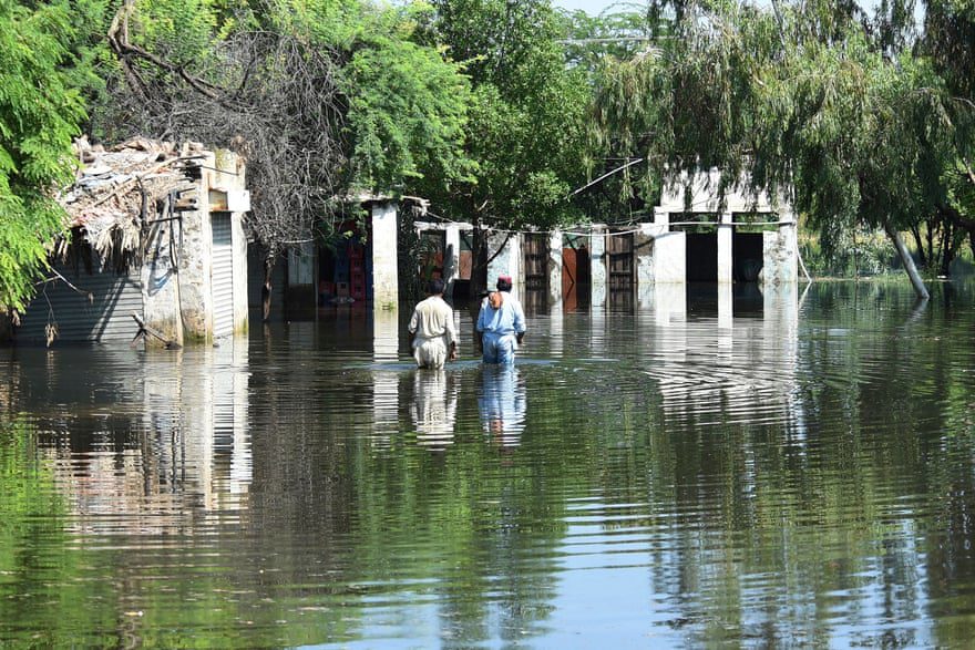 Warga mengarungi banjir di dekat rumah mereka setelah hujan lebat.