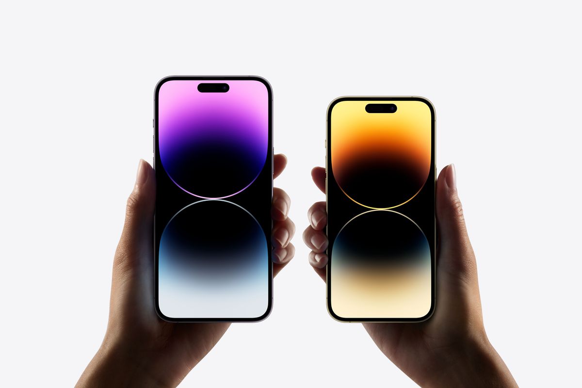 IPhone 14 Pro dan iPhone 14 Pro Max disimpan bersebelahan, layarnya menampilkan latar belakang berwarna-warni.