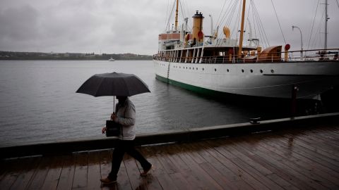 Seorang pejalan kaki melindungi diri dengan payung saat berjalan di sepanjang tepi pantai Halifax dengan hujan sebelum Badai Fiona mendarat di Halifax, Jumat, 23 September 2022.