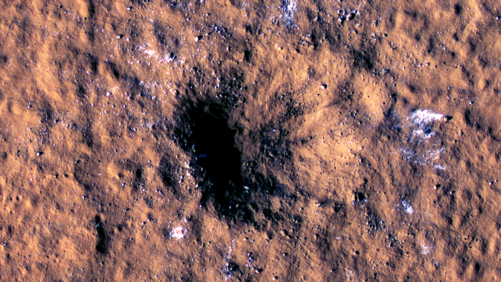 a dark hole gaping in reddish brown surface with weak white patches around it