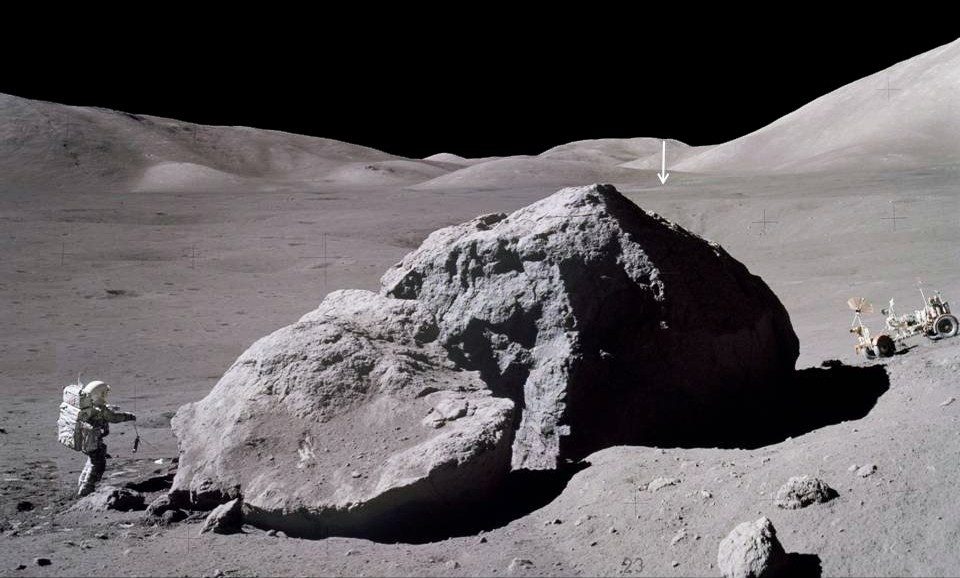 Waktu permukaan Apollo 17, program paling lama di Bulan, adalah tiga hari, dua jam, dan lima puluh sembilan menit.  Gambar menunjukkan Jack Schmidt dari pesawat ruang angkasa Apollo 17 membawa kalajengking kembali ke modul bulan setelah mengamati dan mengambil sampel sisi timur sebuah batu besar.  Panah vertikal di kejauhan menunjuk ke Lunar Module Challenger, yang terletak sekitar 2 mil (3,1 km) jauhnya.
