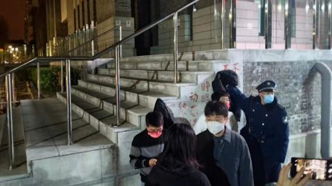 Seorang penjaga keamanan mencoba menutupi spanduk protes terhadap Zero Covid di kampus Universitas Peking di Beijing.